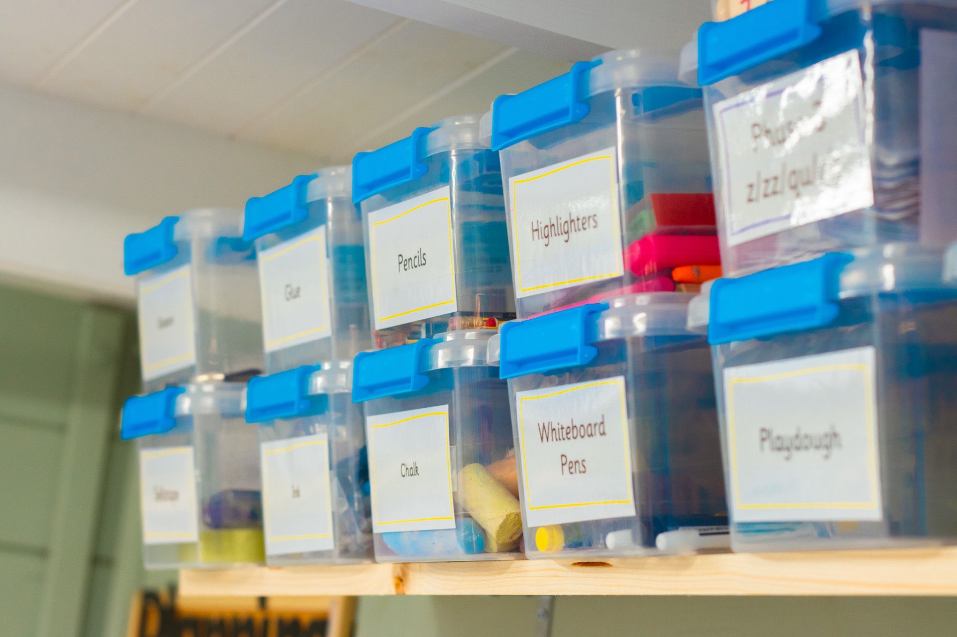 Labelled storage boxes — pencils, glue, highlighters, chalk — in the tutoring room
